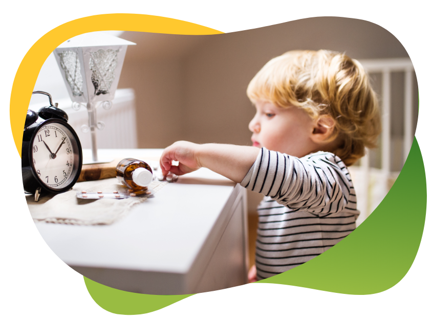 A blonde toddler reaches for a medicine bottle placed on the sideboard