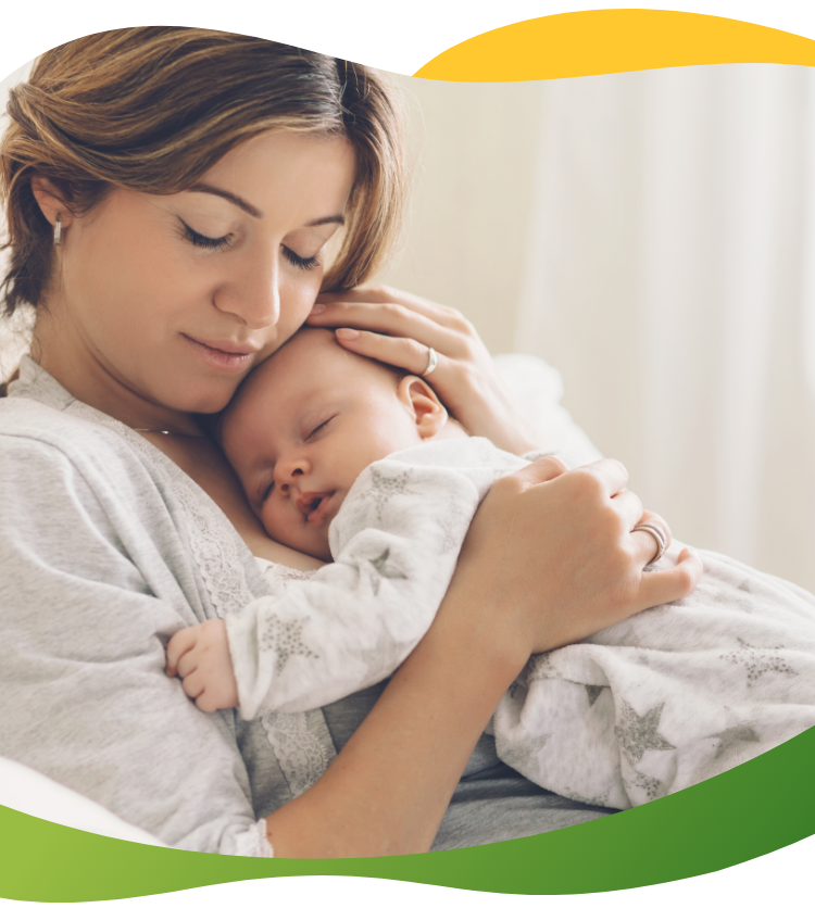 A young mother with her eyes closed pressing her sleeping baby against her chest